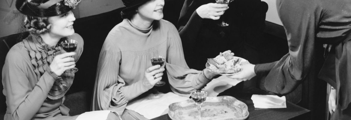 Four women drinking wine, talking in living room