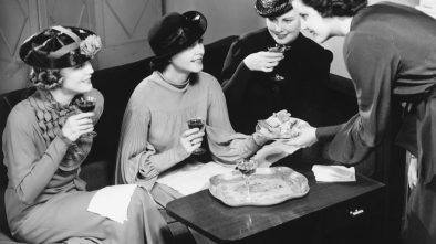 Four women drinking wine, talking in living room